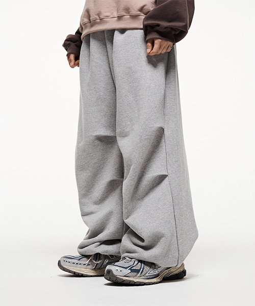Very wide gray sweatpants pooling softly over chunky gray running shoes